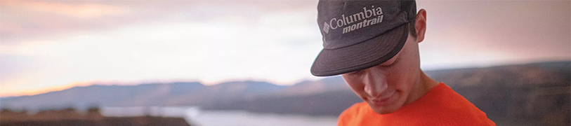 Model wearing a Columbia sportswear hat with a sunset in the backgroun